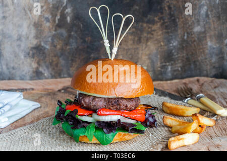 Venison burger in brioche bun with peppery leaf salad, onion and roast peppers Stock Photo