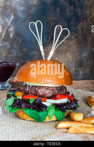 Venison burger in brioche bun with peppery leaf salad, onion, roast peppers and lingonberry sauce Stock Photo