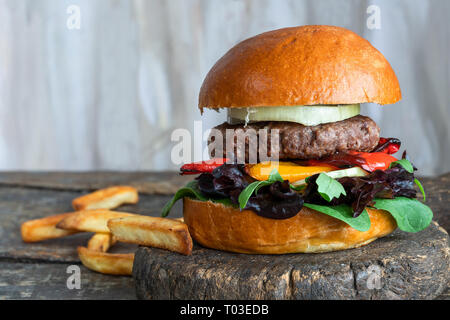 Venison burger in brioche bun with peppery leaf salad, onion and roast peppers Stock Photo