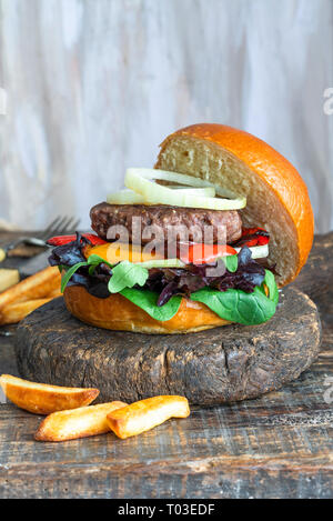 Venison burger in brioche bun with peppery leaf salad, onion and roast peppers Stock Photo