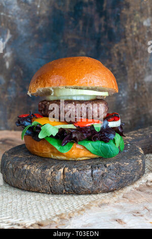 Venison burger in brioche bun with peppery leaf salad, onion and roast peppers Stock Photo