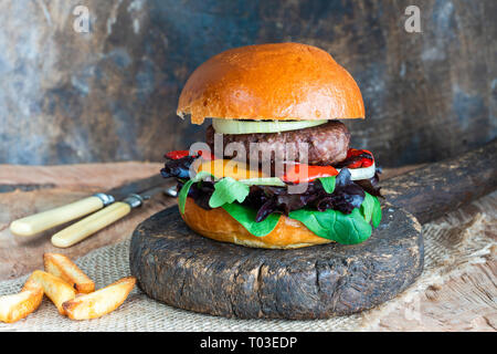 Venison burger in brioche bun with peppery leaf salad, onion and roast peppers Stock Photo