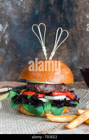 Venison burger in brioche bun with peppery leaf salad, onion, roast peppers and lingonberry sauce Stock Photo