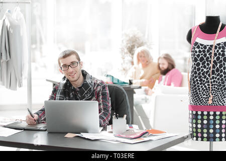 designer using laptop and graphics tablet to create sketches of new clothes Stock Photo