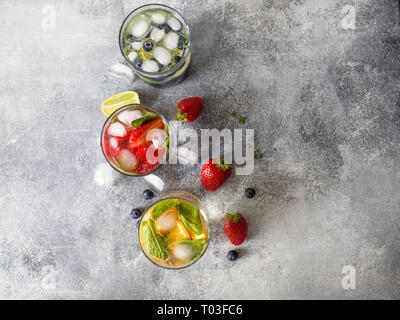 various citrus infused waters, lemonades or mojitos, with lime and blueberries, orange and strawberries and basil in glasses, diet detox beve Stock Photo