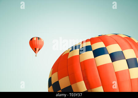Two vibrant hot air balloons in clear sky, one close and one far. Stock Photo