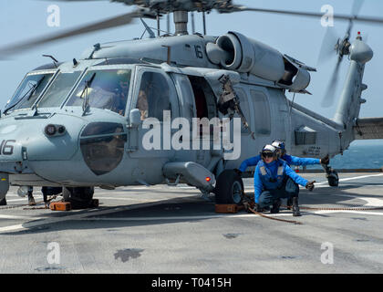 190315-N-AT530-1110 U.S. 5TH FLEET AREA OF OPERATIONS (March 15, 2019) – Sailors give a signal after securing a MH-60S Sea Hawk helicopter during flight operations aboard the Whidbey Island-class amphibious dock landing ship USS Fort McHenry (LSD 43). Fort McHenry is part of the Kearsarge Amphibious Ready Group and, with the embarked 22nd Marine Expeditionary Unit, is deployed to the U.S. 5th Fleet area of operations in support of naval operations to ensure maritime stability and security in the central region, connecting the Mediterranean and the Pacific through the western Indian Ocean and t Stock Photo