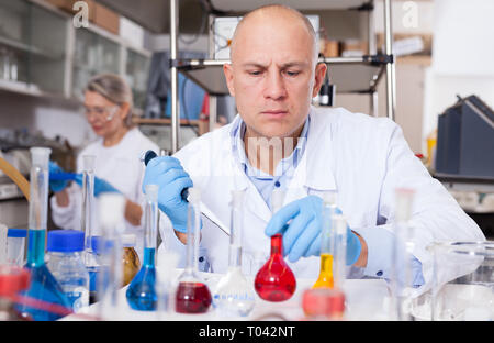 Experienced chemist working in research laboratory, analyzing liquid samples Stock Photo