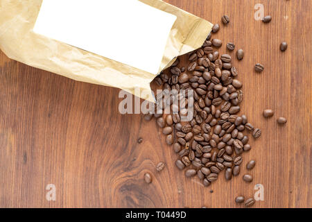 coffee bag lie on wodden table with spild coffee beans around product label cutout Stock Photo