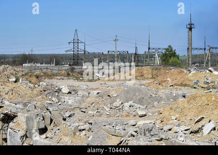 The remains of the Foundation of the building in the form of concrete debris mixed with clay on the background of the electrical substation. Backgroun Stock Photo