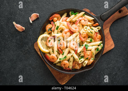 Penne Pasta with Prawns or Shrimps on black, top view, copy space. Lemon pasta with sauteed shrimps, fresh seafood. Stock Photo