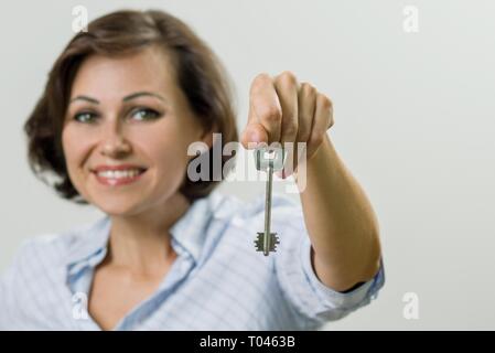 Portrait of beautiful adult woman holding key. Concept of sale opportunity realtor investment. Stock Photo
