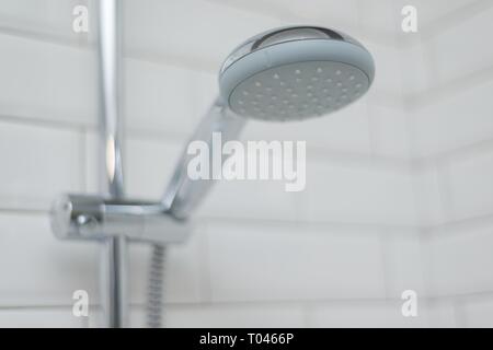Close-up of chrome shower in the bathroom covered decorative ceramic tiles with white glossy bricks Stock Photo