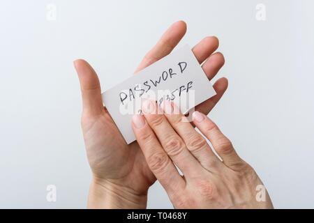 Woman's hand holds a password on paper, that covers the password with finger. Stock Photo