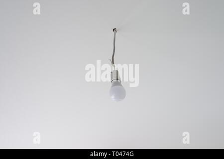 LED light bulb on white ceiling. Temporary lighting during repair Stock Photo