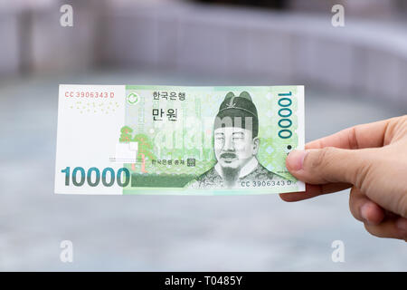 Man hold south korea banknote 10000 won on blurred background Stock Photo