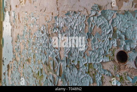 The cracks from the paint of the wall od the house that was damaged by the bombs during the war in ukraine Stock Photo