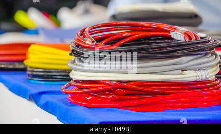 Rolled colored wires on the table there are red white and blue color wires Stock Photo