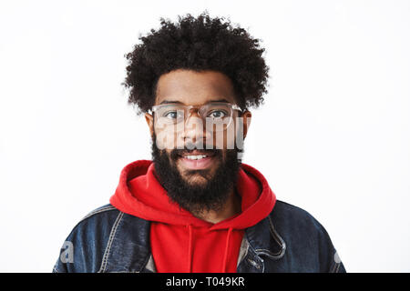 Headshot of ambitious and handsome young creative african american freelancer with pierced nose and afro hairstyle in glasses smiling joyfully at Stock Photo