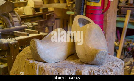 The crafted wooden shoes on the factory with lots of woods and crafts inside Stock Photo