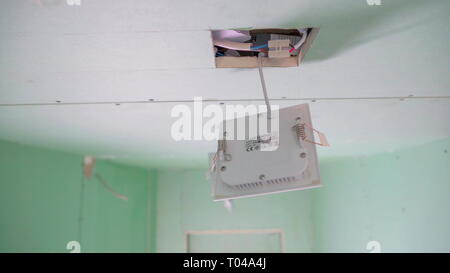 The white wires inside the ceiling with the white box hanging on the square hole of the ceiling of the house Stock Photo