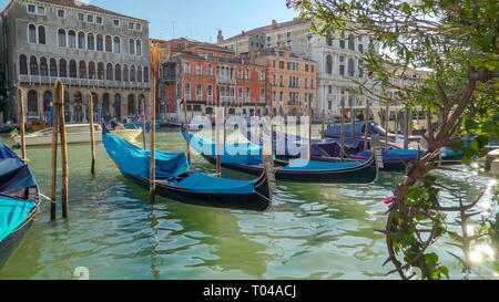 Some of the Venetian gondolas being tied on the poles being covered on the canal of Venice  in Italy Stock Photo