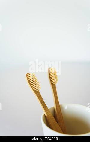 Two wooden toothbrushes in ceramic cup at bathroom. Stock Photo