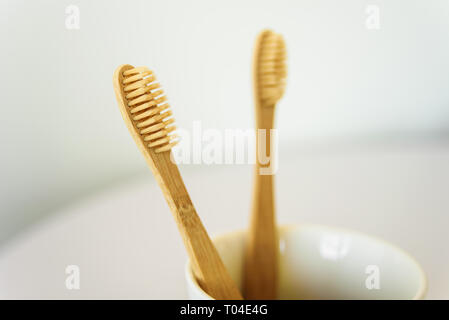 Two wooden toothbrushes in ceramic cup at bathroom. Stock Photo