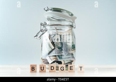 us dollars bill in glass jar and word budget made of wooden blocks Stock Photo