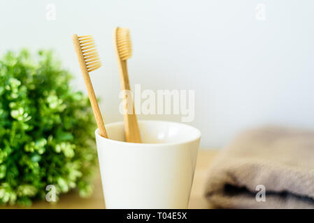 Two wooden toothbrushes in ceramic cup at bathroom. Stock Photo