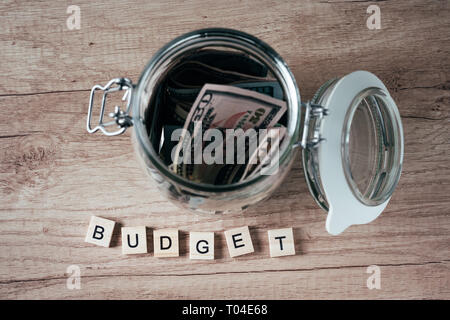 word budget made of wooden blocks and glass jar filled with dollar banknotes Stock Photo