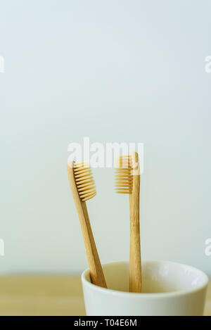 Two wooden toothbrushes in ceramic cup at bathroom. Stock Photo