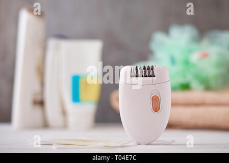 Epilator and wax strips on background with shampoo and towel, selective focus Stock Photo