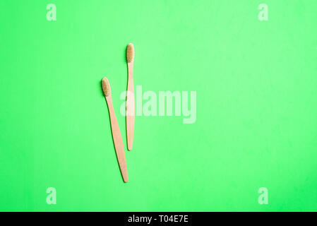 Two wooden toothbrushes on light green background Stock Photo