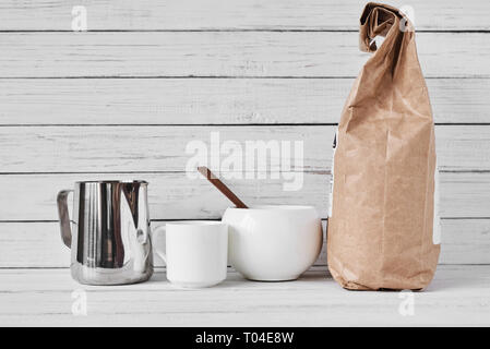 Coffee cup, craft paper bag and stainless pitcher on white background, copy space Stock Photo