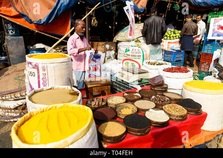 Colorful fruit and spice market with vendors trading and people transporting goods in the streets of Dhaka, Bangladesh Stock Photo