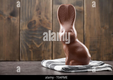 Delicious chocolate Easter bunny, eggs and sweets on rustic background Stock Photo