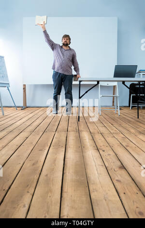 Presentation concept. Lecturing process. Presentation of new business. Portrait of young confident man with heap of books. Expression of feelings Stock Photo