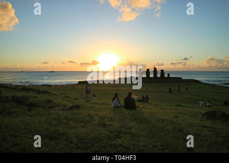 Groups of people watching sunset at Ahu Tahai on the Pacific ocean coast, Archaeological site on Easter Island, Chile Stock Photo