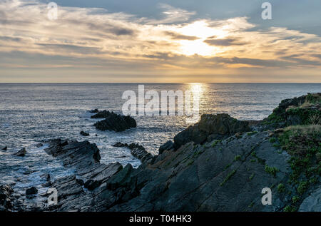 A view of Hartland Quay, Devon, England, UK during the golden hour of the sunset. Reflection and low light as the sun dips below the horizon Stock Photo