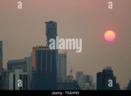Stunning setting sun amongst the skyscrapers in Bangkok urban, Thailand Stock Photo