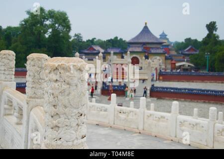 Close up on a decorative, carved marble column. Ornate, beautiful blue and red painted roofs of Beijing's Temple of Heaven out of focus in background. Stock Photo