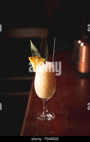 Pina colada cocktail on bar with pineapple garnish Stock Photo