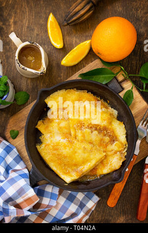 Homemade French pancakes - Crepe Suzette with orange syrup for a delicious breakfast. Top view flat lay background. Stock Photo