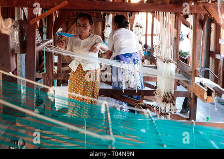 Burmese worker make silk from lotus in traditional wooden weaving and handworking factory in Inle Lake, Myanmar. Stock Photo