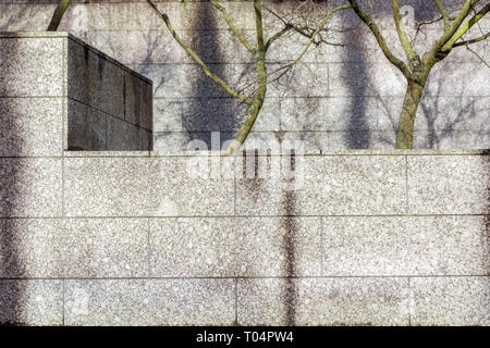 Cityscape with a wall lined with marble stone slabs and trees in the background. Stock Photo