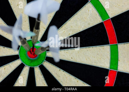 three darts thrown at the bulls eye of a dartboard Stock Photo