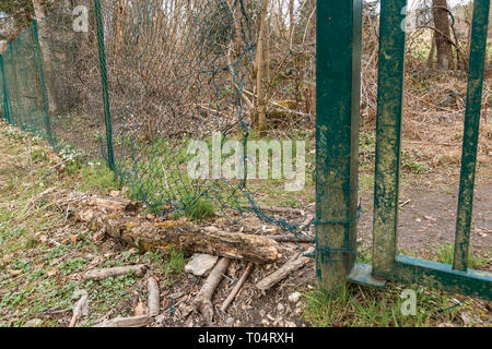 Security breach into wire mesh fence through big hole Stock Photo