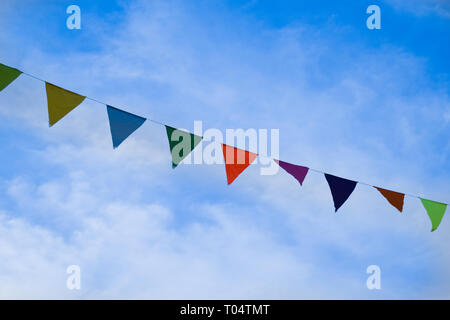 Colored triangular flags on bright blue sky background, festive decorations Stock Photo