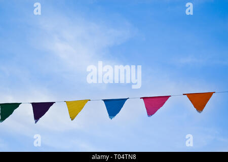 Colored triangular flags on bright blue sky background, festive decorations Stock Photo